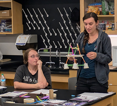 Two participants sharing their moon lander design and talking about the testing and redesign phase.